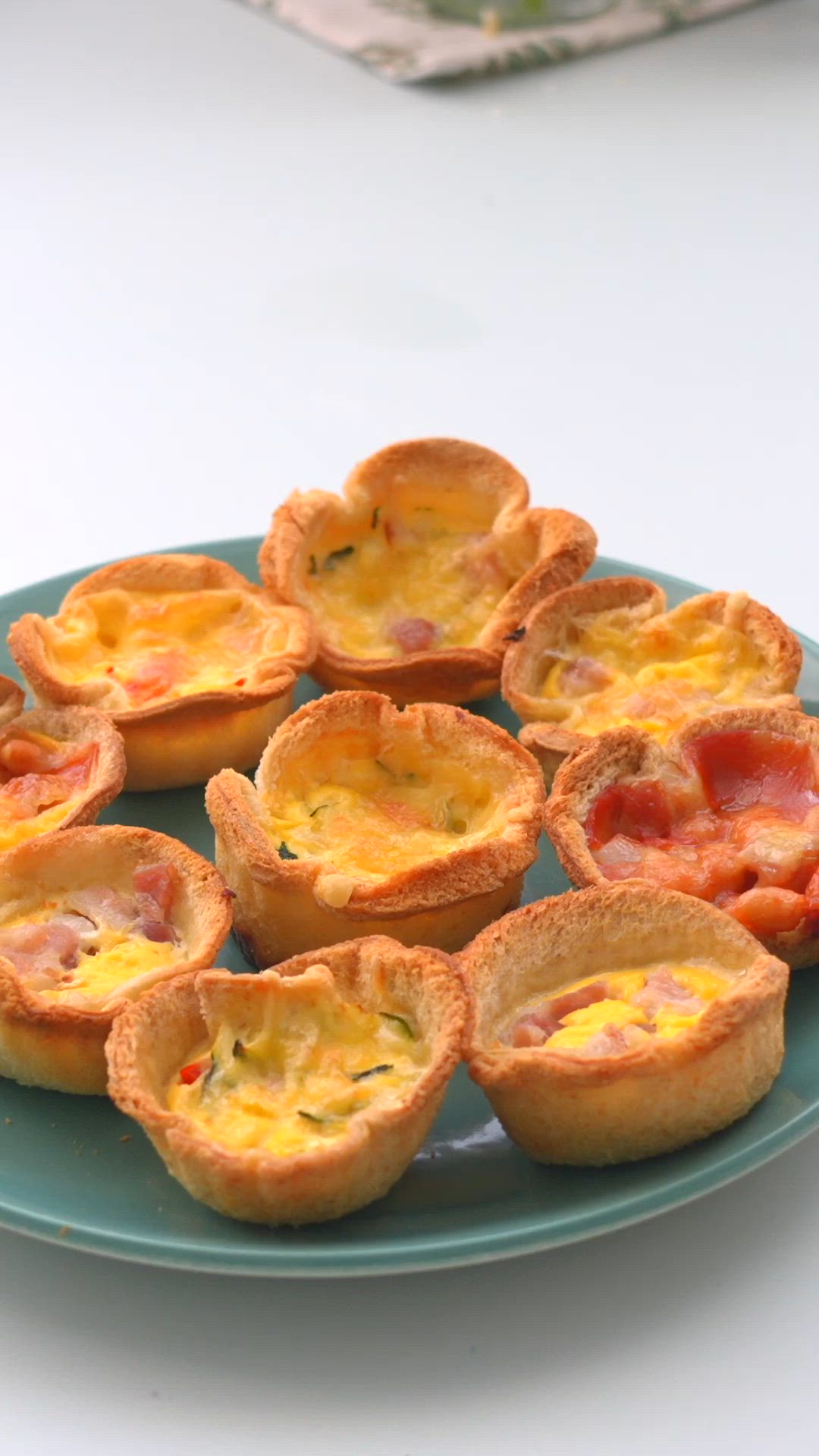 This may contain: mini quiche cups on a blue plate with the words bread cases aka mini quiches