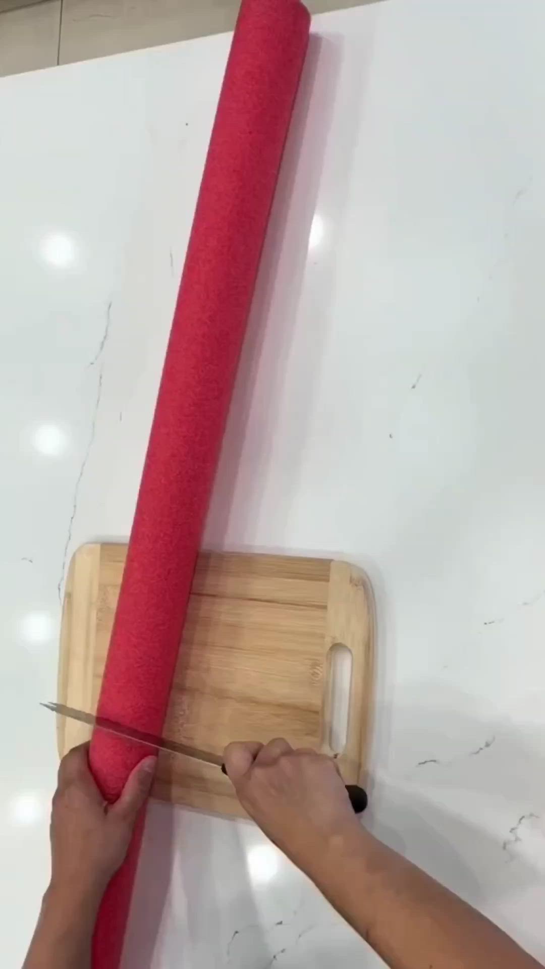 This may contain: a person using a pair of scissors to cut up a piece of red fabric on a cutting board