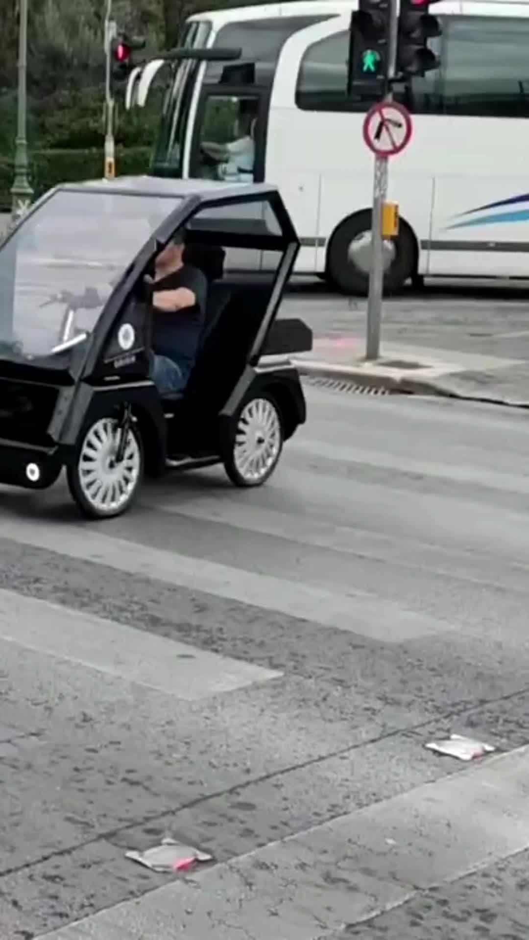 This may contain: a man driving an electric car down the street