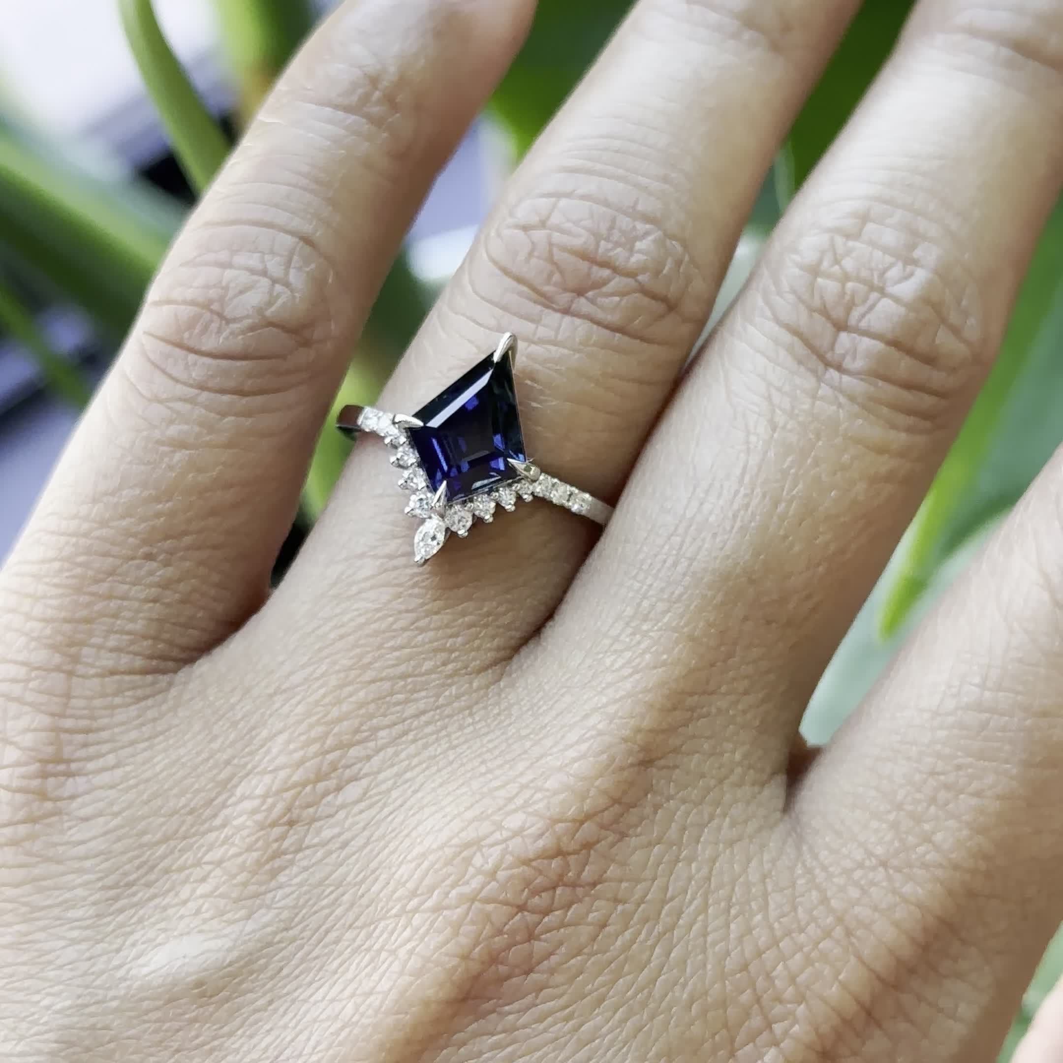 This may contain: a woman's hand with a ring on it and a blue stone in the middle