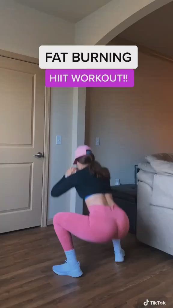 This may contain: a woman in pink leggings and black top doing squat exercises with her hands behind her head