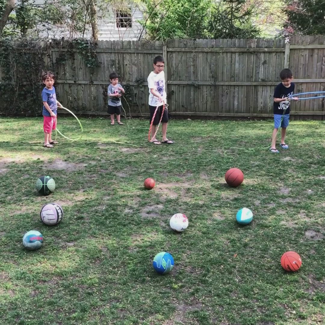 This may contain: several children playing with different colored balls in the yard