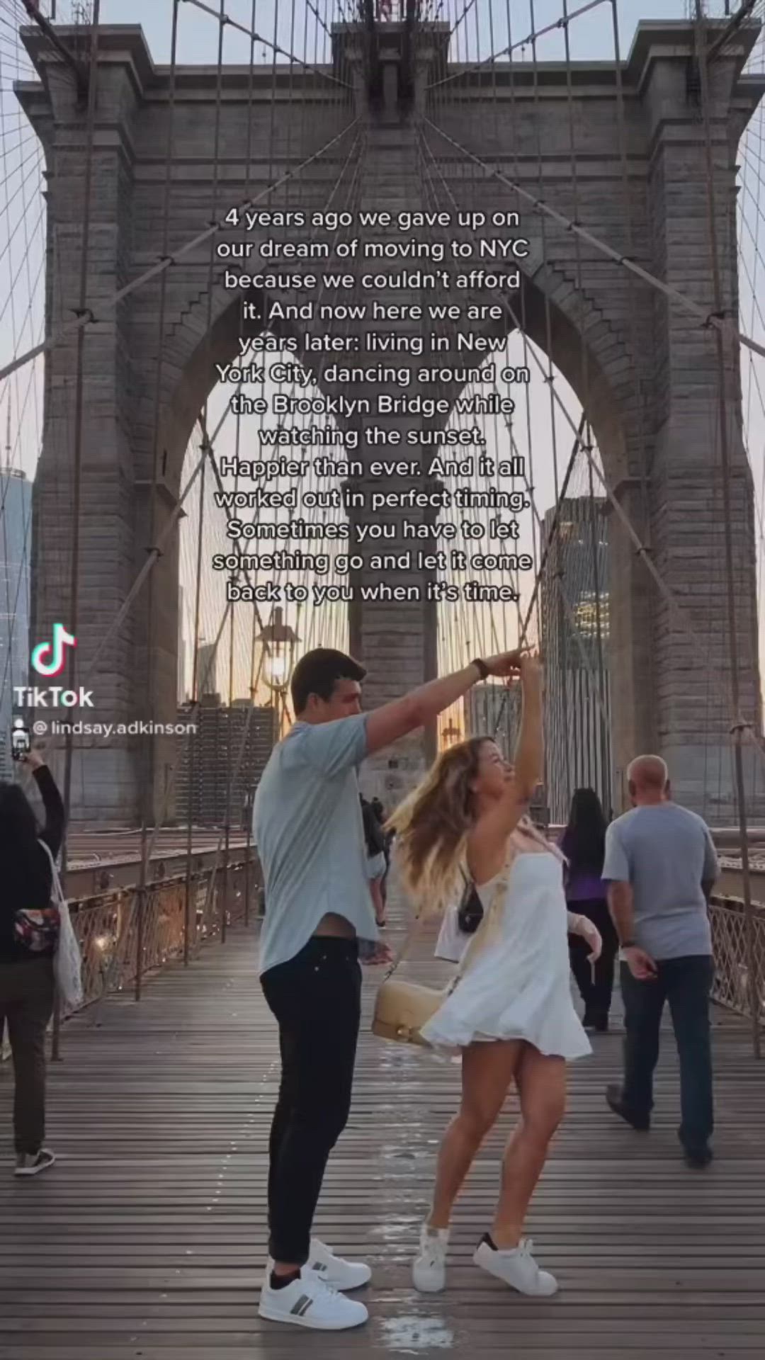 This may contain: two people dancing on a bridge in front of the brooklyn bridge with an inspirational quote