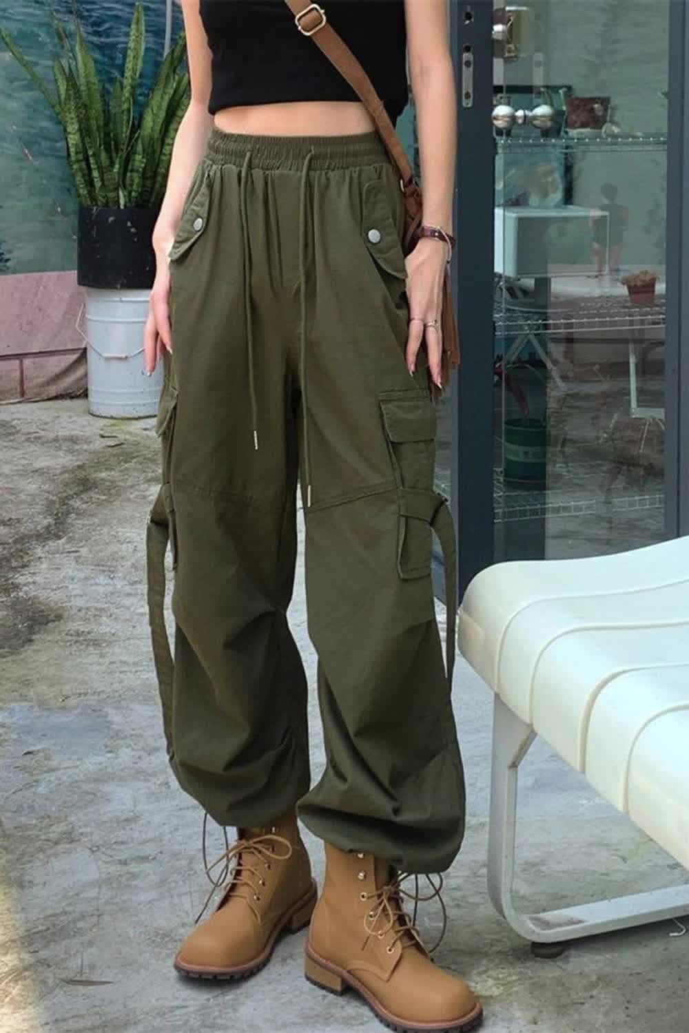 This contains: Elevate your streetwear game with these Women High Waist Cargo Pants. Designed with fashion in mind, these pants feature a trendy lace-up design and large pockets for your essentials. The high waist design and comfortable fit make them perfect for everyday wear. Upgrade your wardrobe with these versatile and stylish pants.