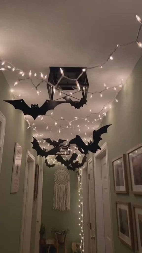 This may contain: some lights are hanging from the ceiling in a hallway with bats on it and other decorations