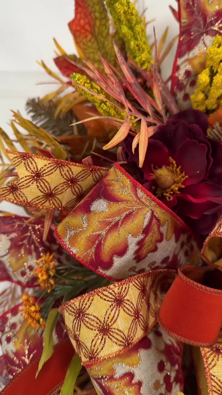 This may contain: the fall swag has been decorated with red, yellow and orange flowers on it