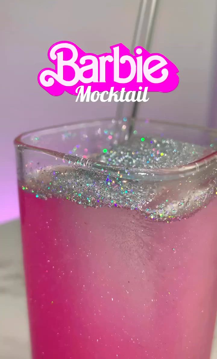 This may contain: a close up of a drink in a glass on a table with sparkles around it