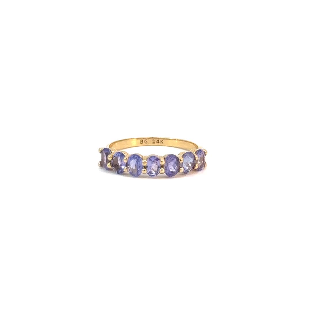 This may contain: a yellow gold ring with five tan and purple stones on the band, set in 18k yellow gold