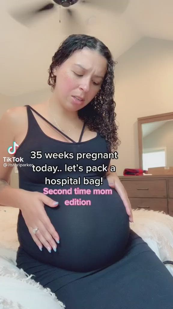 This may contain: a pregnant woman sitting on top of a bed next to a fan with the caption, 35 weeks pregnant today it's pack a hospital bag