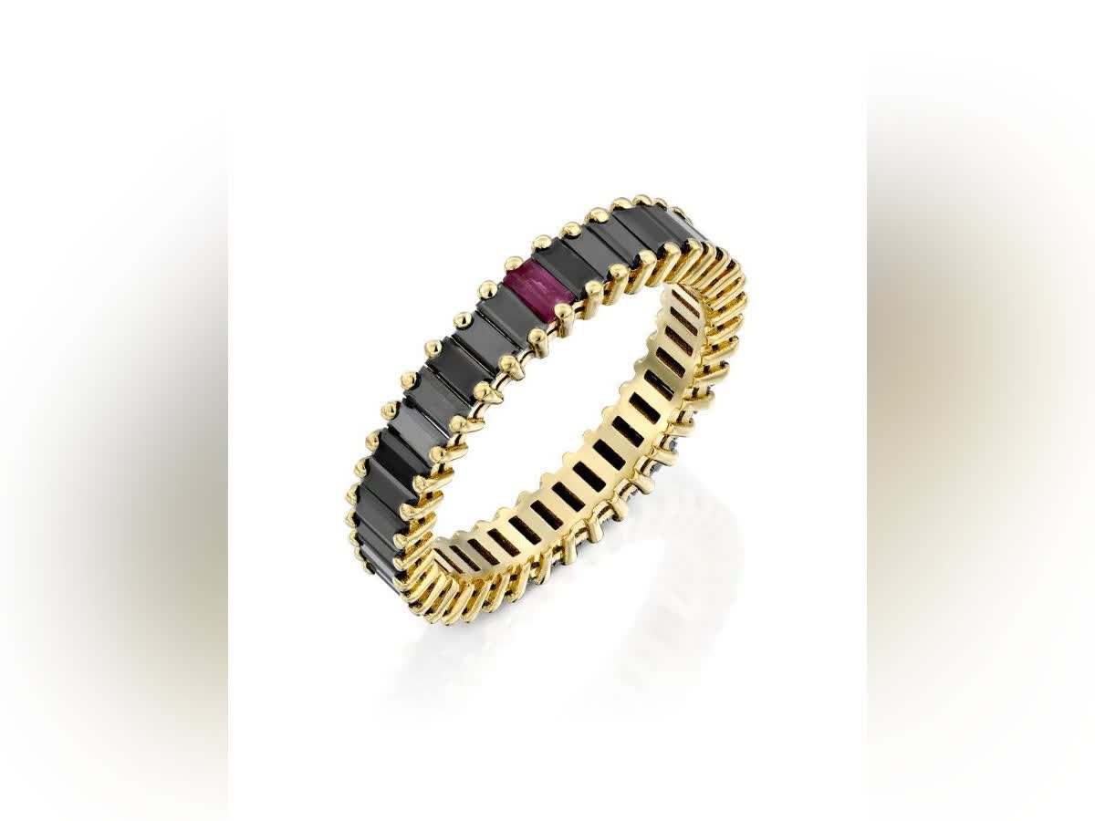 This may contain: a gold ring with black and red stones