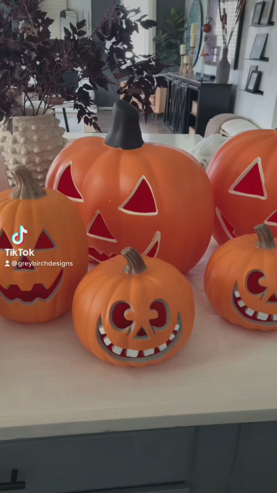 This may contain: four pumpkins with faces carved into them on a counter in front of a potted plant