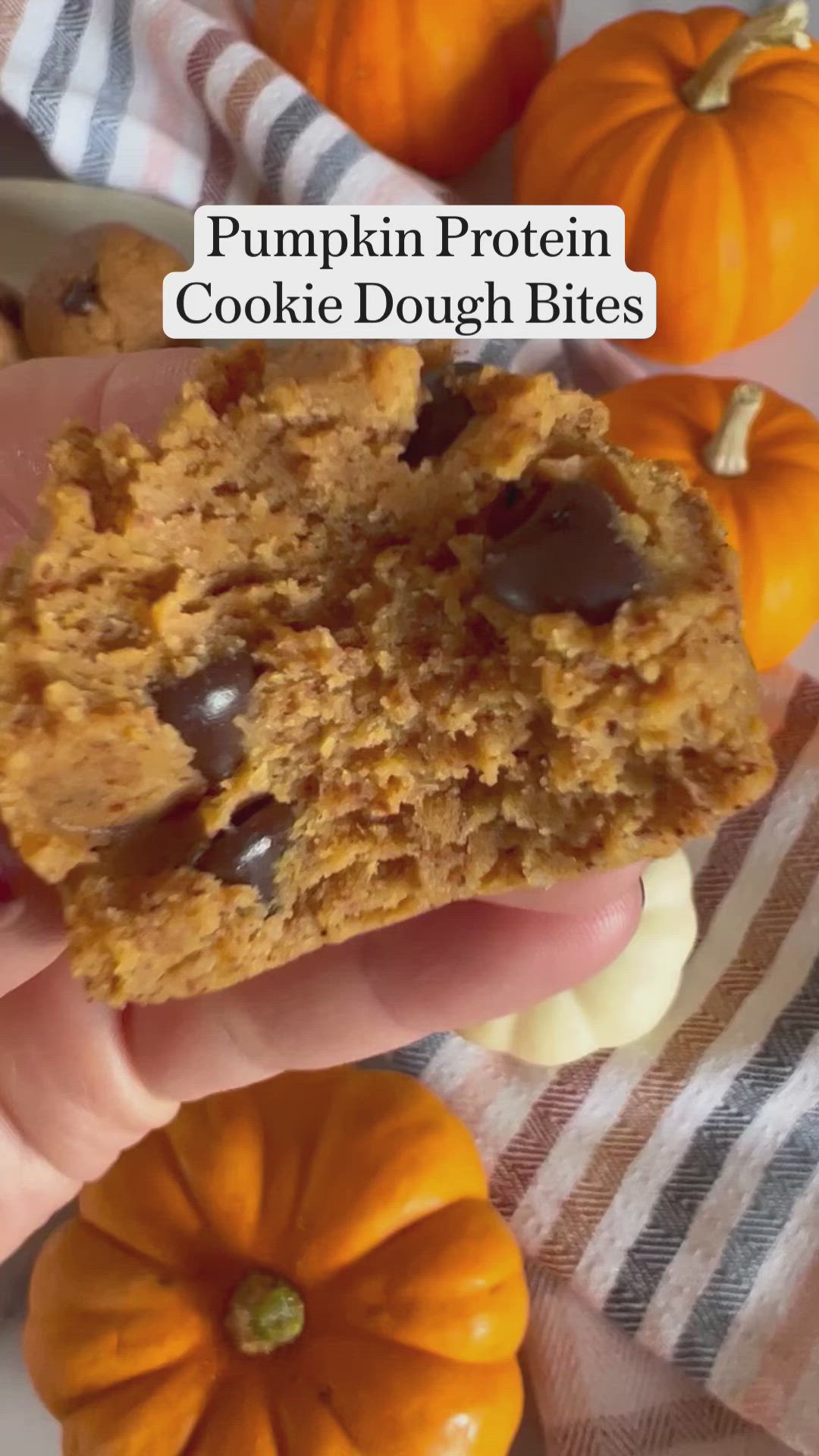 This may contain: pumpkin protein cookie dough bites are being held by someone's hand with mini pumpkins in the background