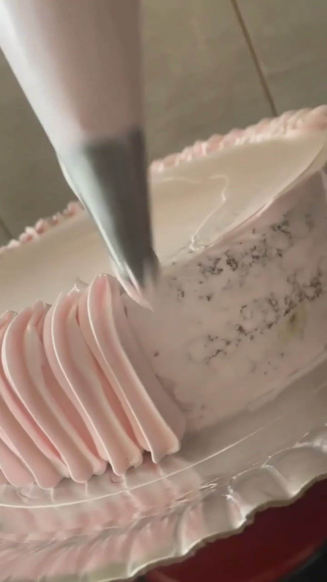 This may contain: a cake being frosted with pink icing