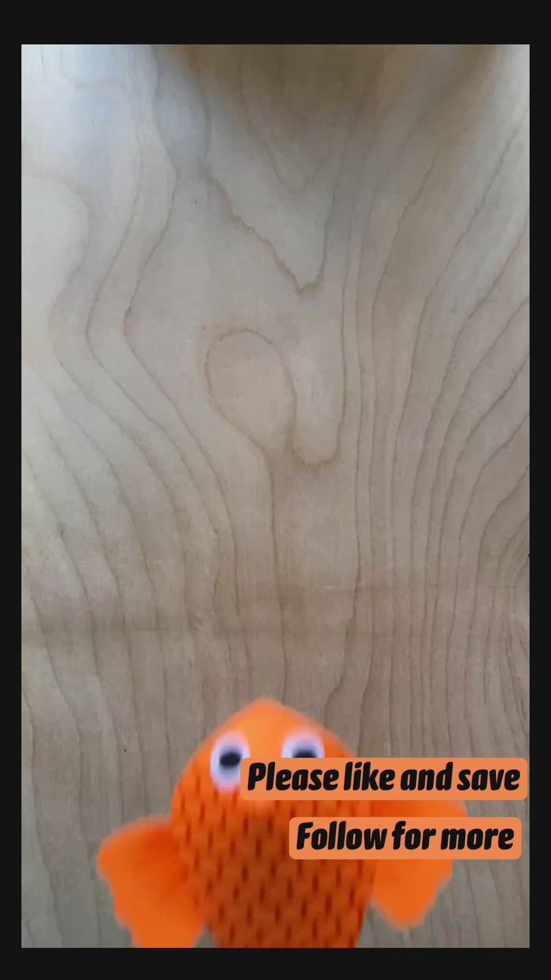 This may contain: an orange toy fish sitting on top of a wooden floor next to a sign that says please like and save follow for more