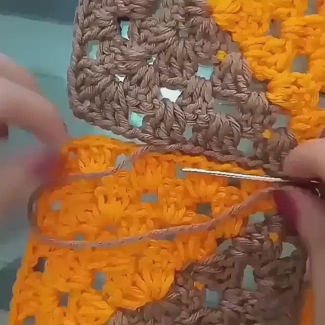 This may contain: someone is crocheting an orange piece of yarn