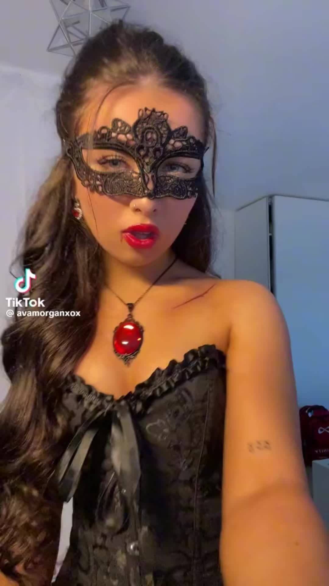 This may contain: a woman wearing a black mask with red lips