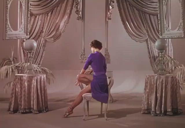 This may contain: a woman in a purple dress sitting on a chair