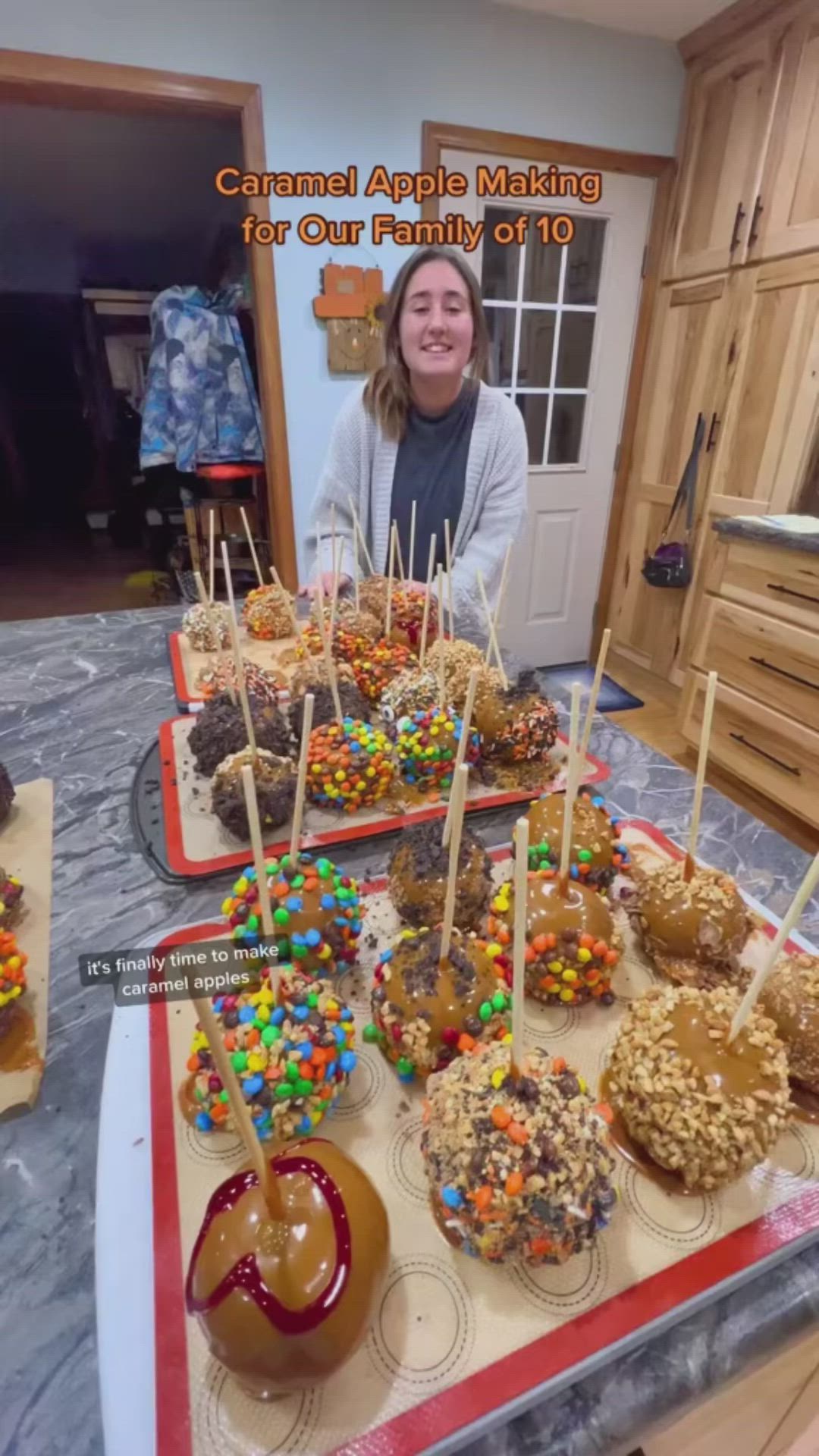 This may contain: a woman sitting in front of a table filled with cake pops and candy covered donuts