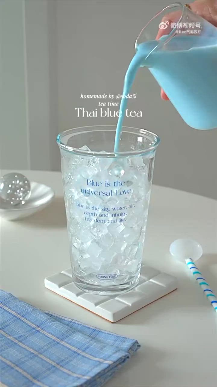 This may contain: a person pouring milk into a cup on top of a white table next to a toothbrush