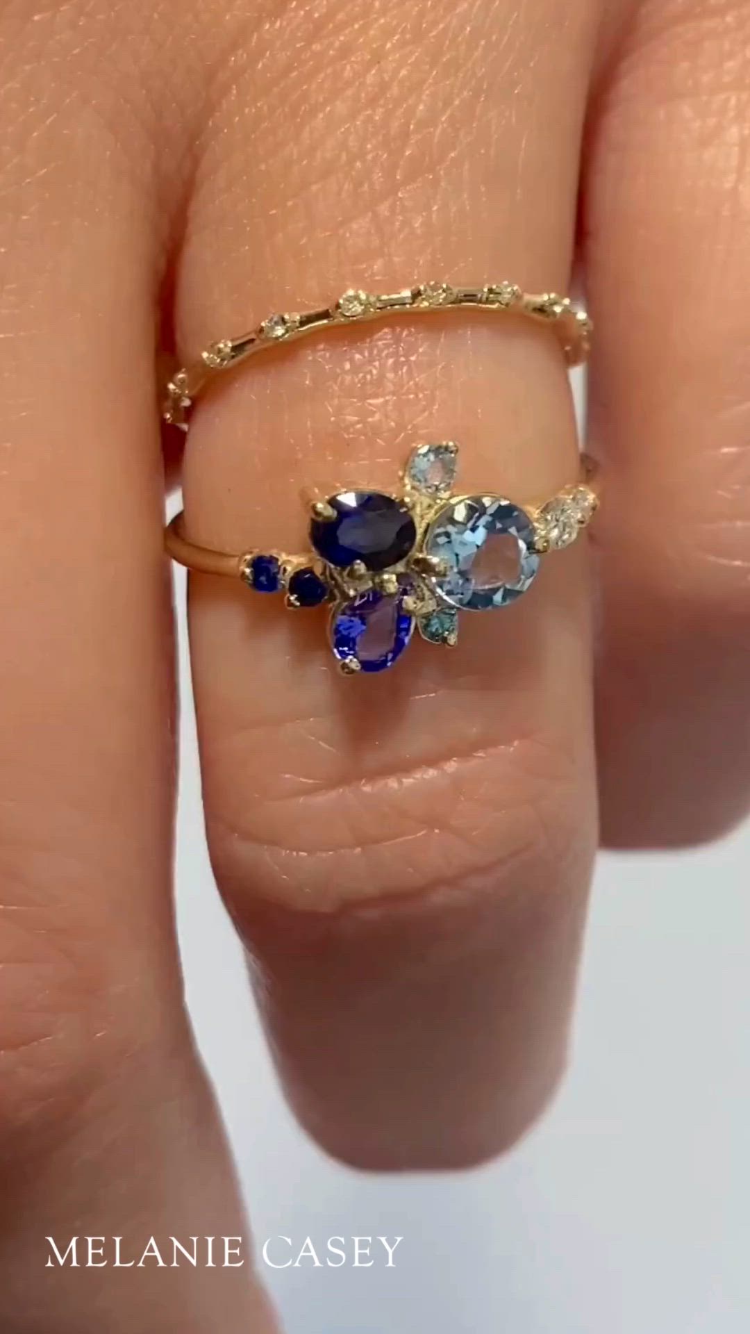 This contains: A blue gemstone cluster ring is worn by a woman's hand.