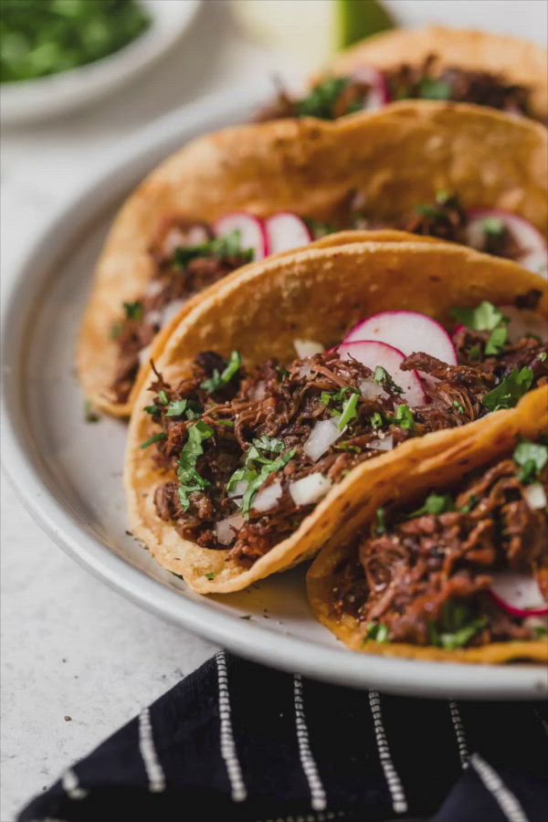 This may contain: three tacos on a plate with radishes and cilantro in the background