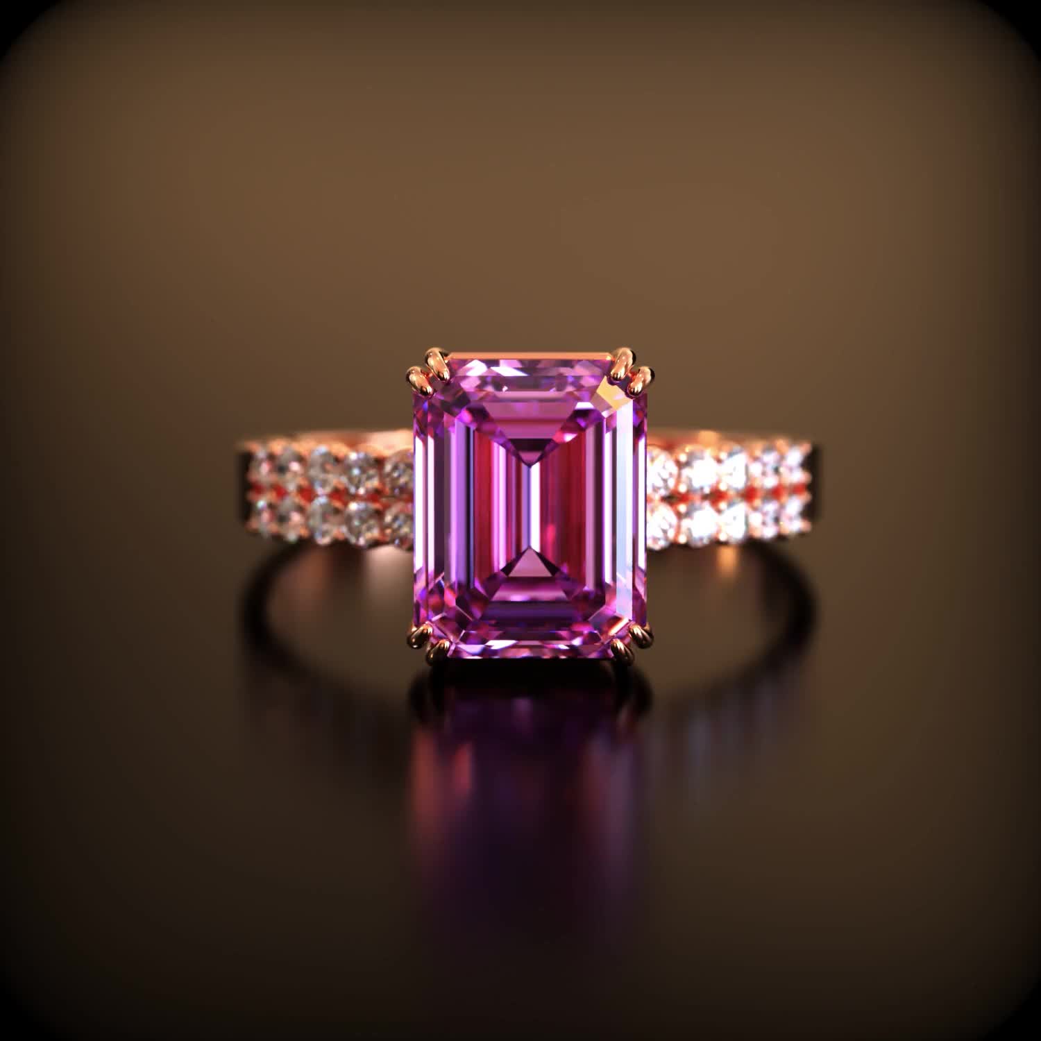 This may contain: a fancy pink diamond ring on a black surface with diamonds around the band and side stones