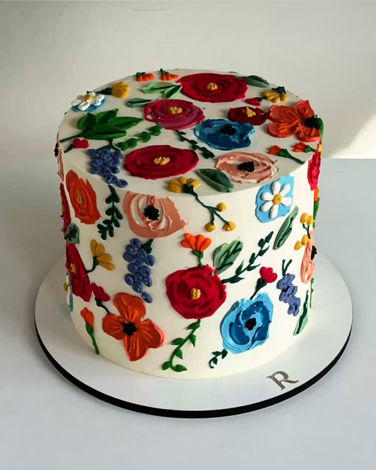 This may contain: a white cake with colorful flowers on it