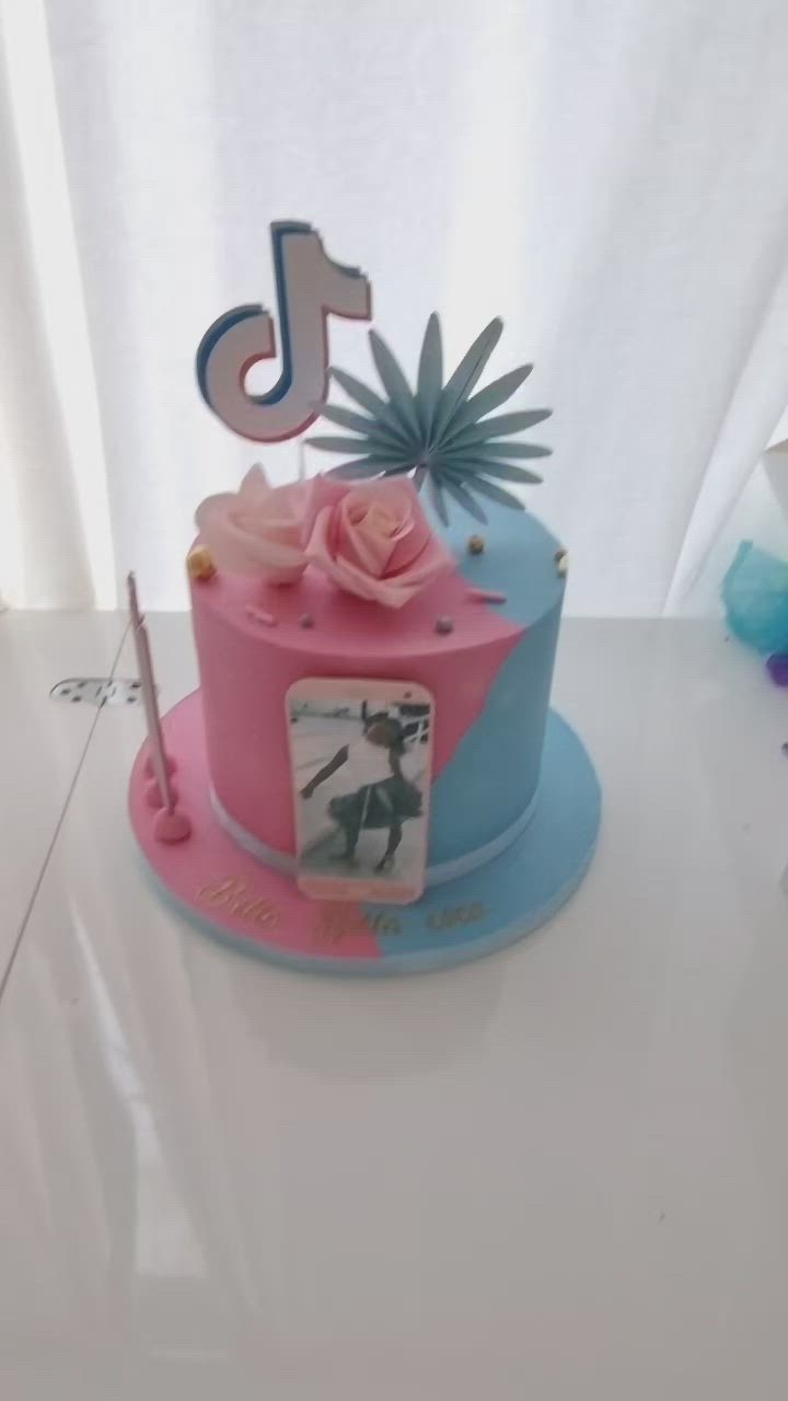 This may contain: a pink and blue birthday cake with a photo on top