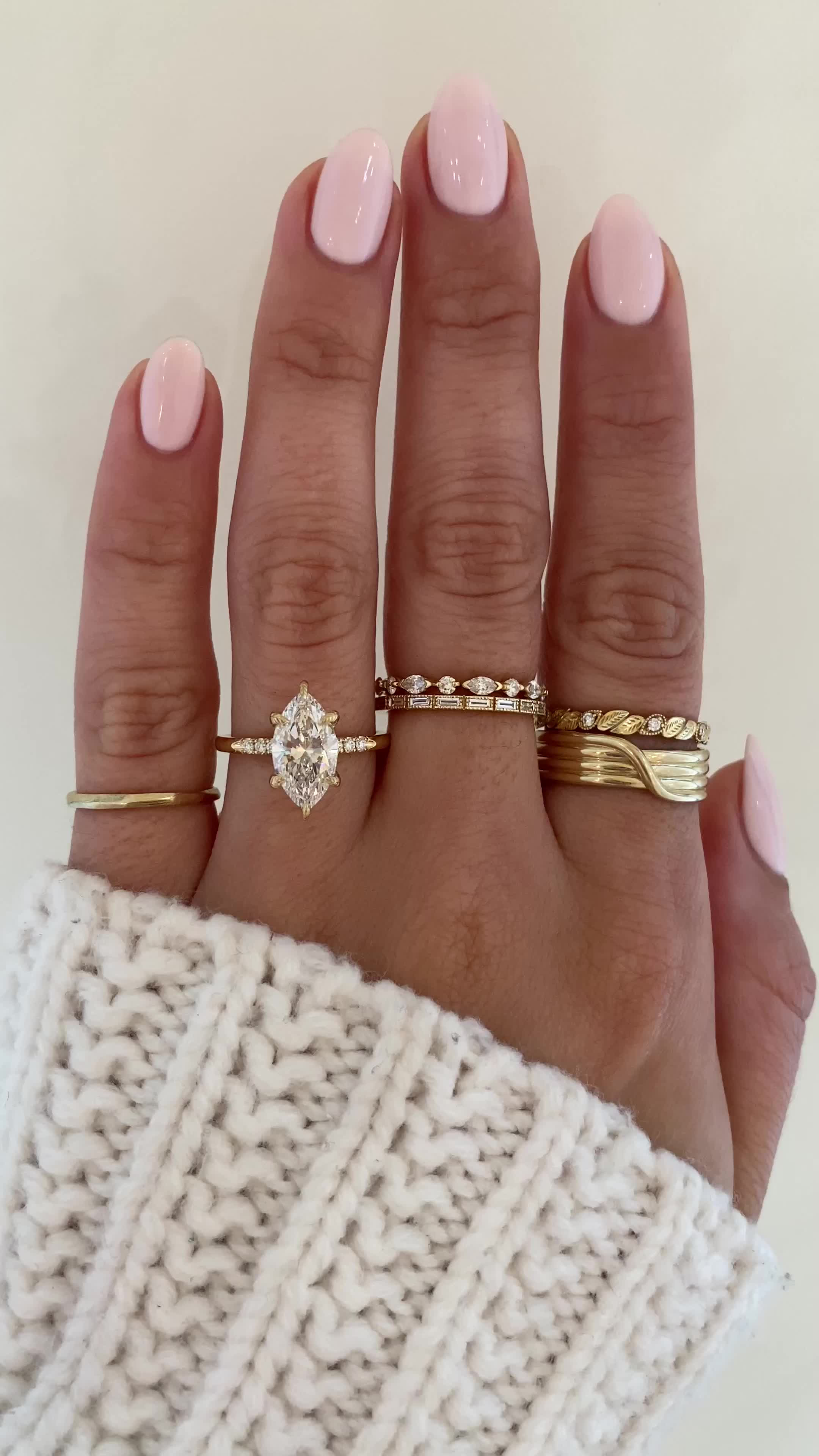 This may contain: a woman's hand with three different rings on her fingers and one is wearing a sweater