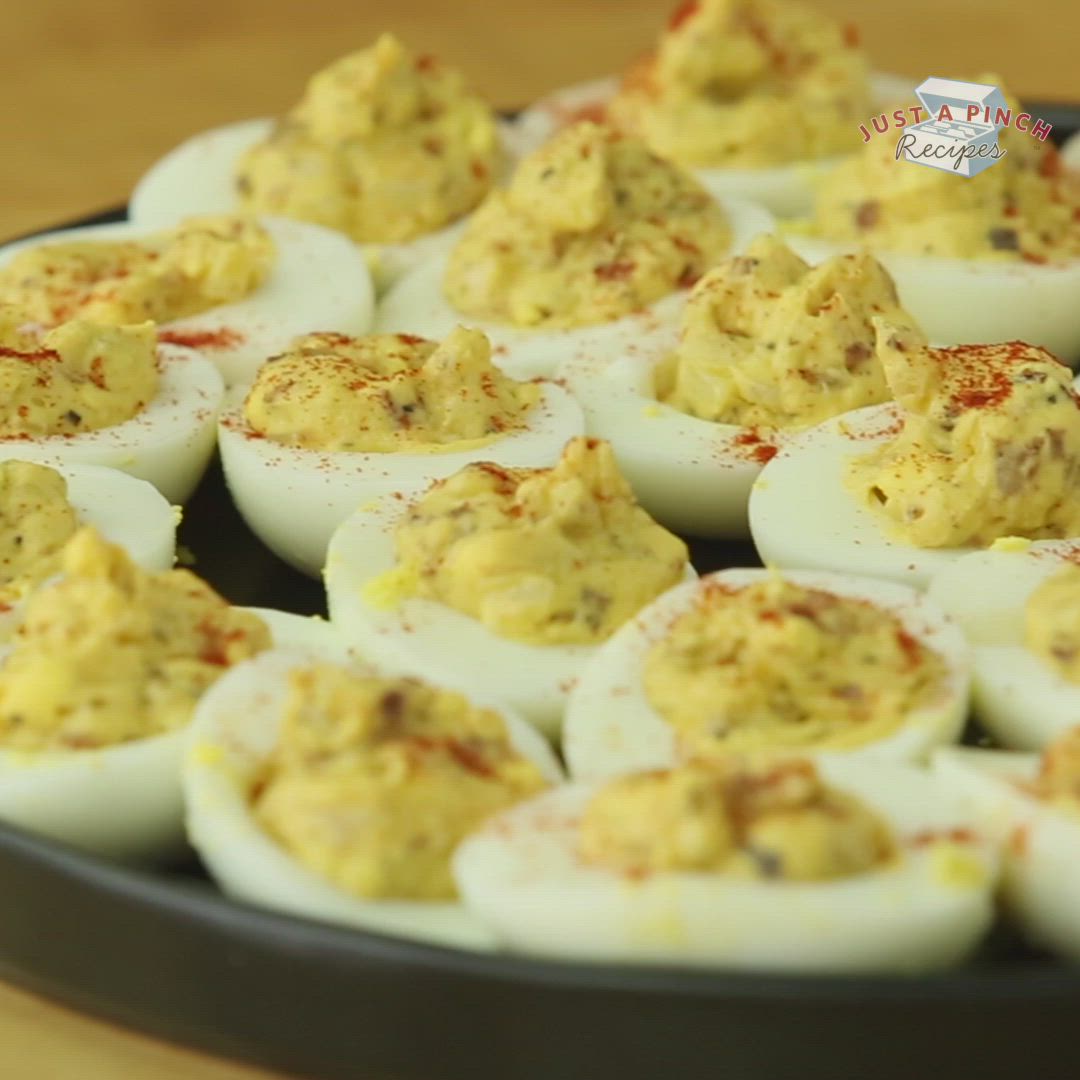 This may contain: deviled eggs are arranged on a black plate