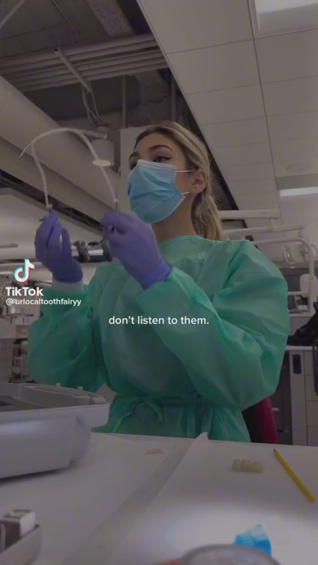 This may contain: a woman wearing a face mask and gloves in a room with other medical equipment on the table