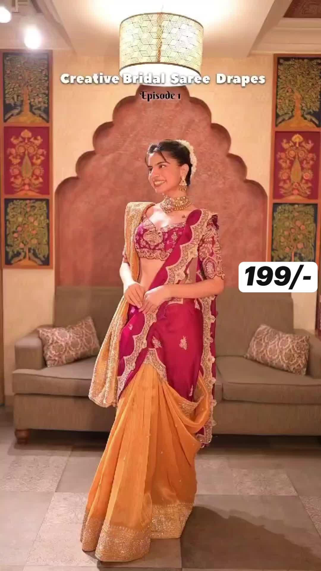 This may contain: a woman in a red and yellow sari standing next to a couch with pillows on it