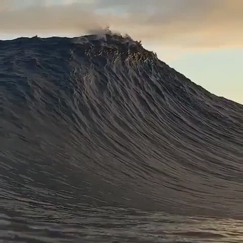 This may contain: a man riding a wave on top of a surfboard