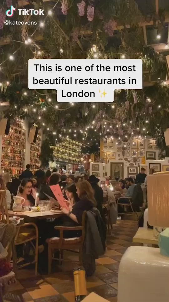 This may contain: people sitting at tables in a restaurant with lights strung from the ceiling and decorations on the walls