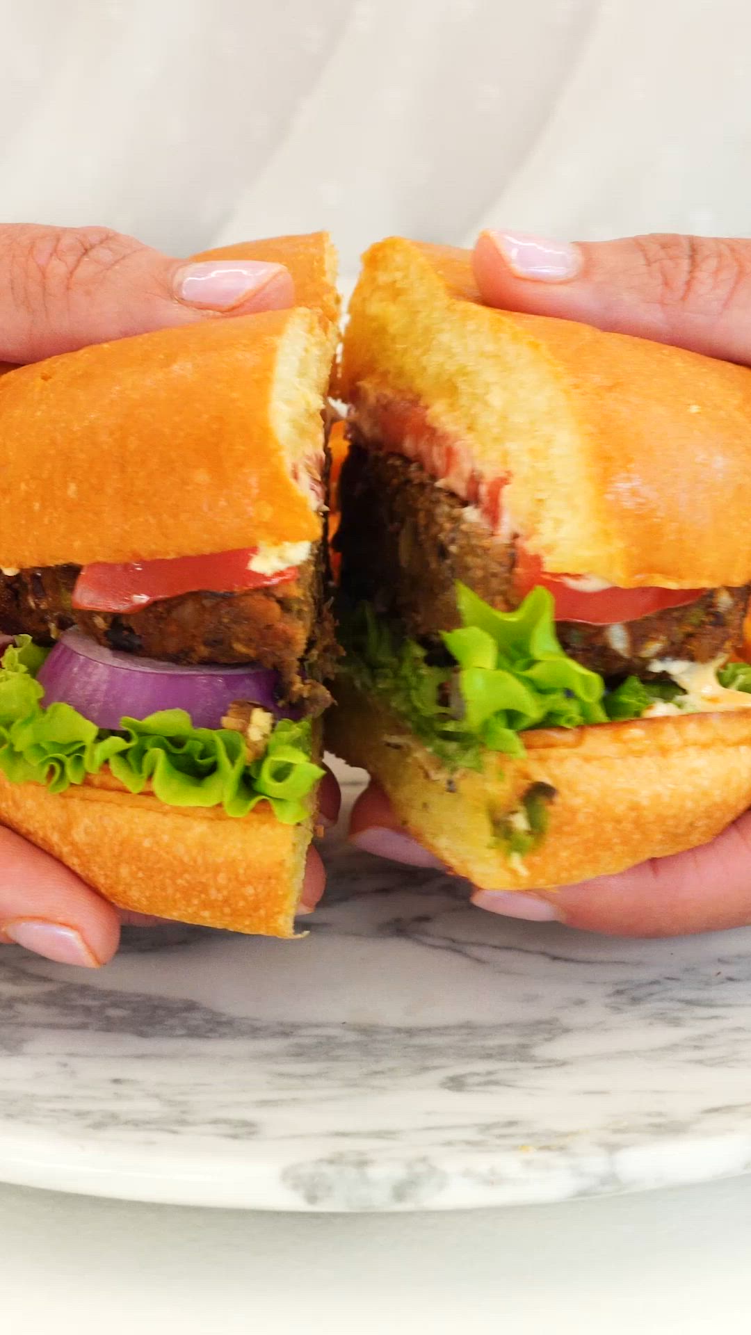 This may contain: two hands holding sandwiches on a marble plate