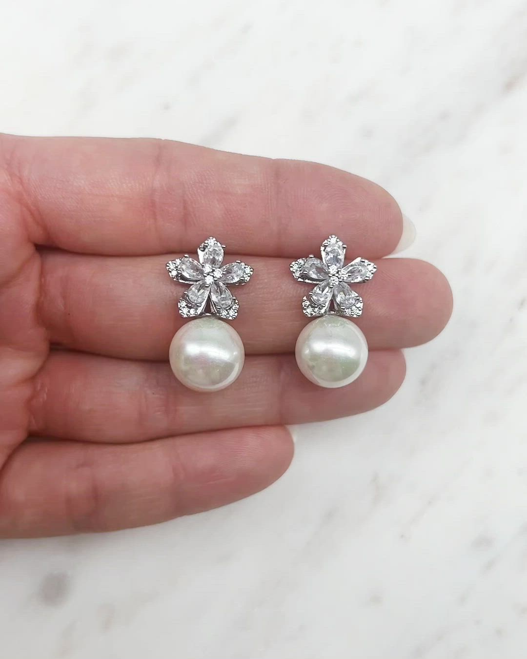 Elegant & sophisticated, our Cecilia Pearl Stud Earrings are designed with CZ stones in a flower design that are accented with round pearl drops. Cubic zirconias & round, off white pearls Measures about 0.5" x 1" length Hypoallergenic, lead-free & nickel-free Style #4390 Featured Bride: @jamielbonfante