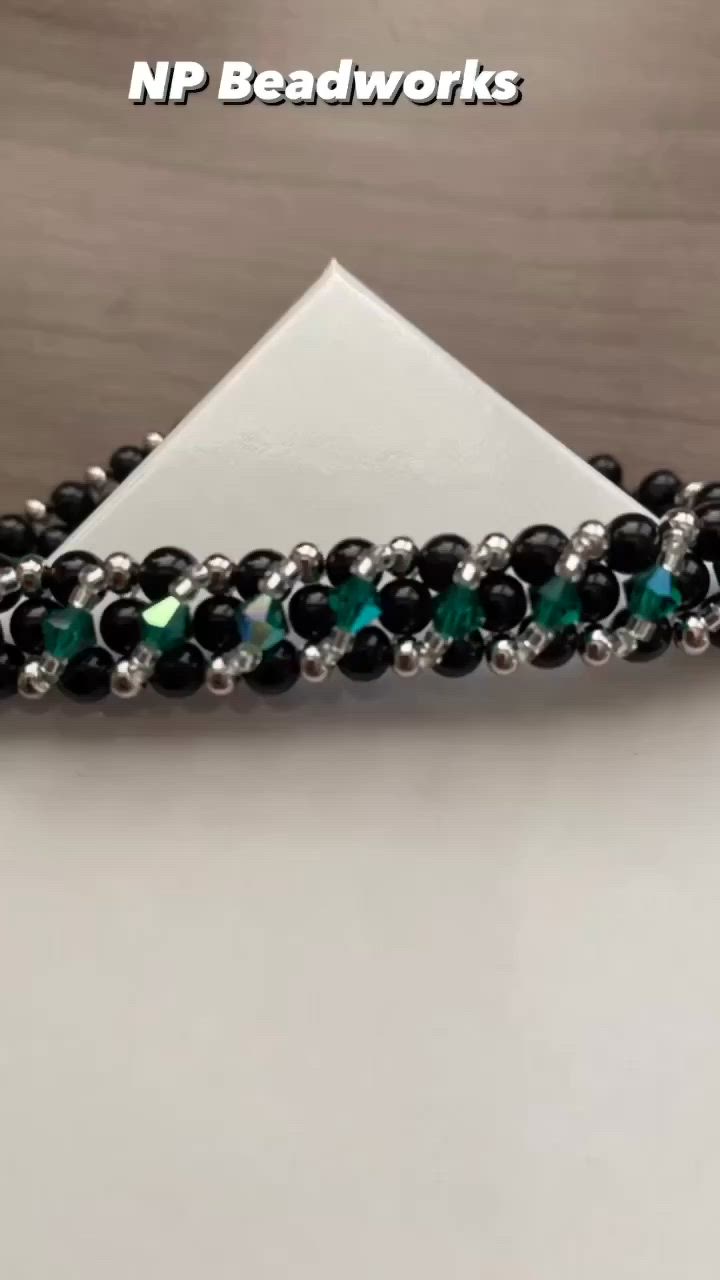 This contains: Black tourmaline beads woven with green crystal and silver colored beads.