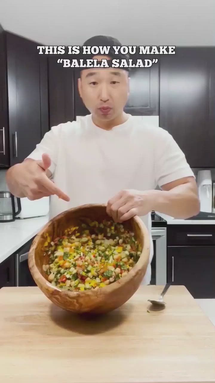 This may contain: a man holding a wooden bowl filled with different types of vegetables on top of a table