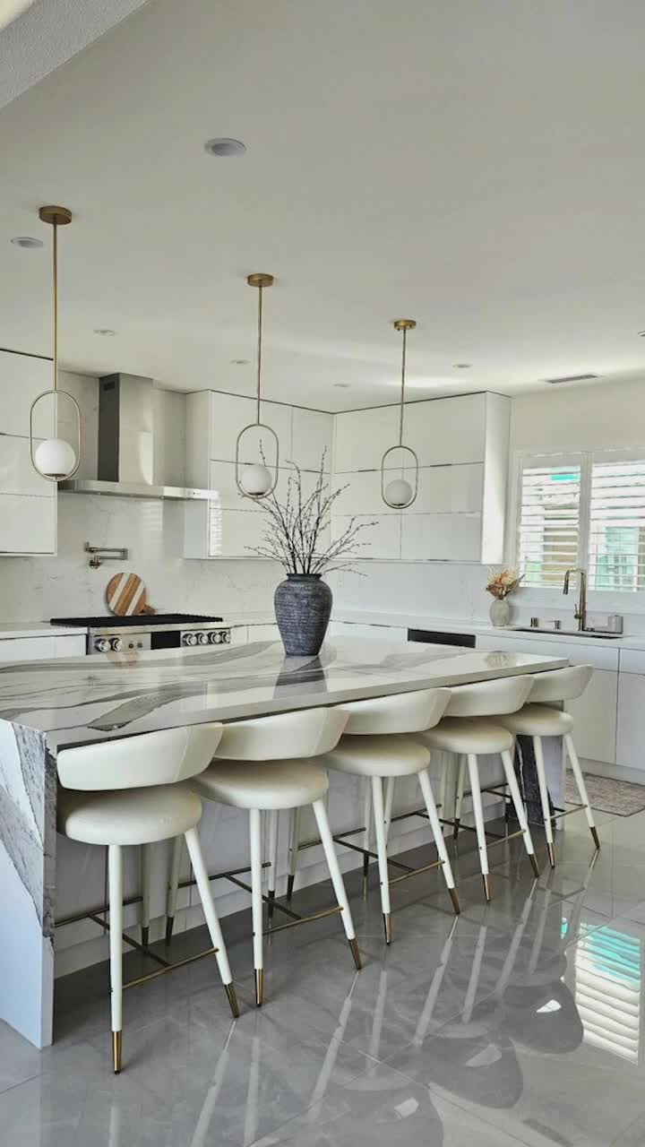 This may contain: a kitchen with marble counter tops and white chairs