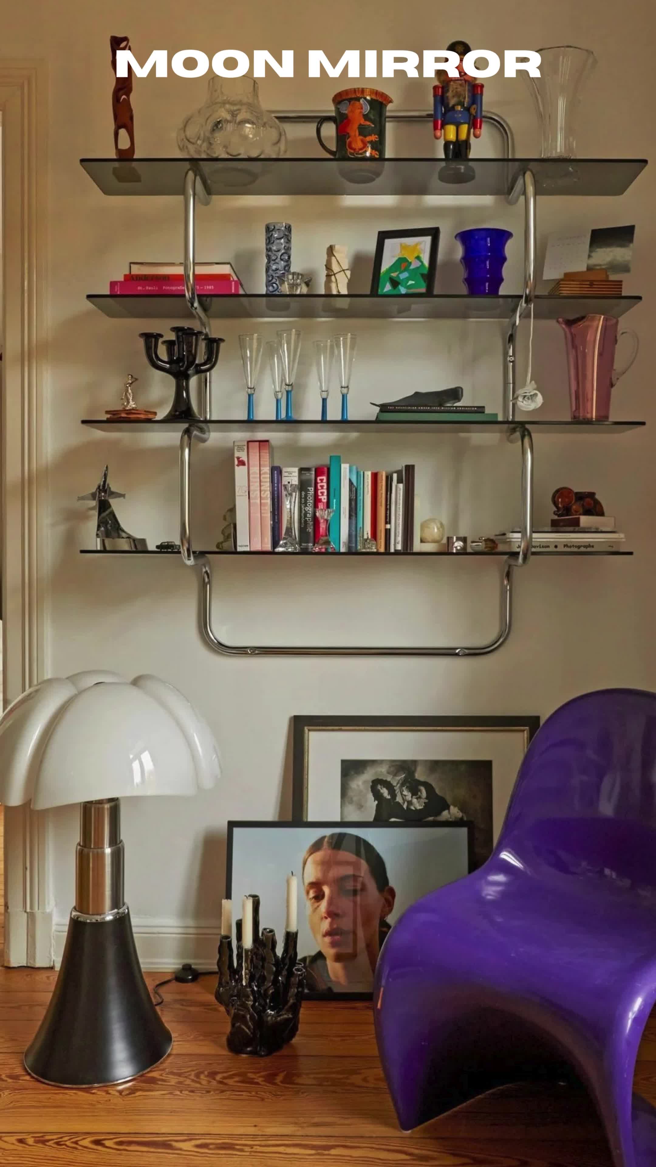 This may contain: a purple chair sitting in front of a shelf filled with books and other items on top of a wooden table