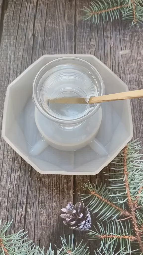 This may contain: a glass cup and saucer on a wooden table with pine cones in the background