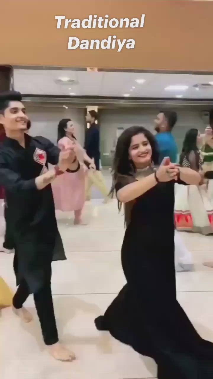 This may contain: two people are dancing on the dance floor with other people in the background and one is wearing a black dress