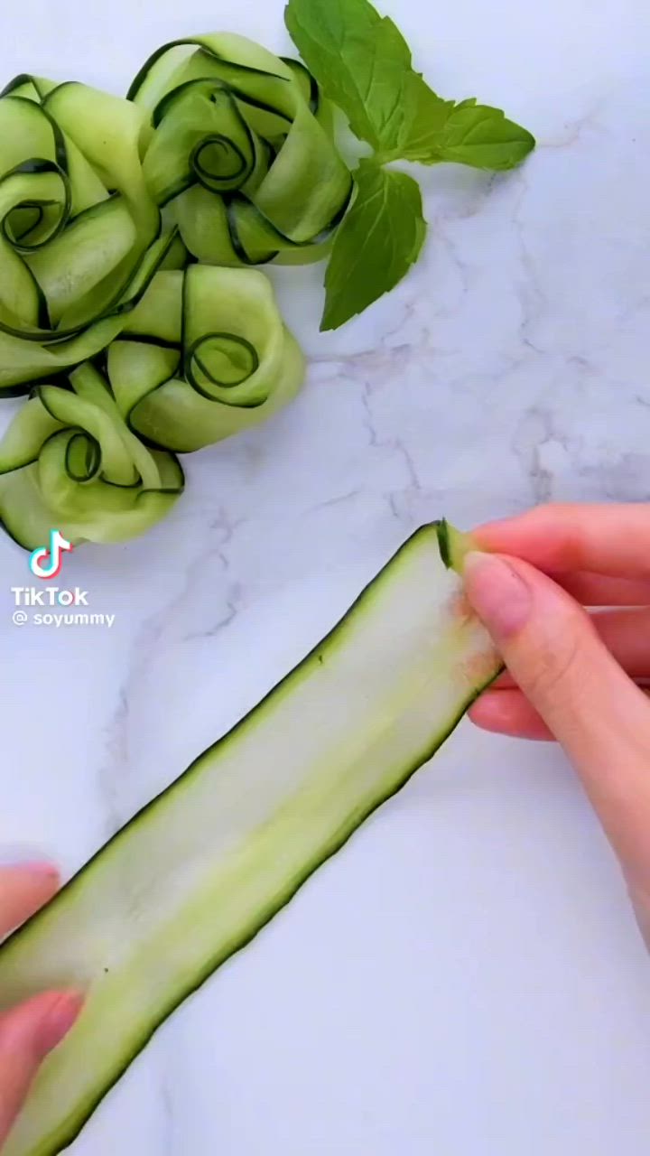 This may contain: someone is cutting cucumbers into small pieces on a white counter top with green leaves