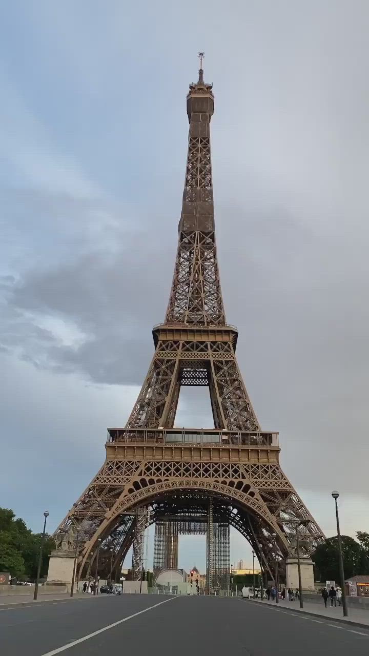 This may contain: the eiffel tower is very tall and has a clock on it's side