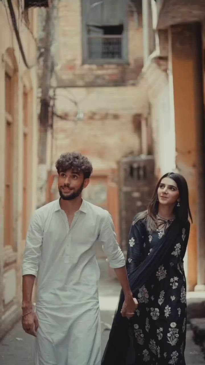 This may contain: a man and woman are walking down the street holding hands in front of an old building