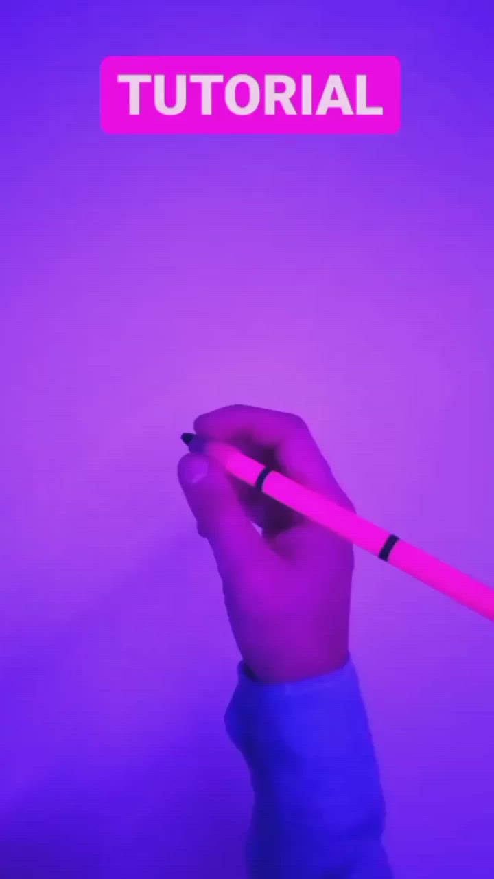 This may contain: a hand holding a pink pen in front of a purple background