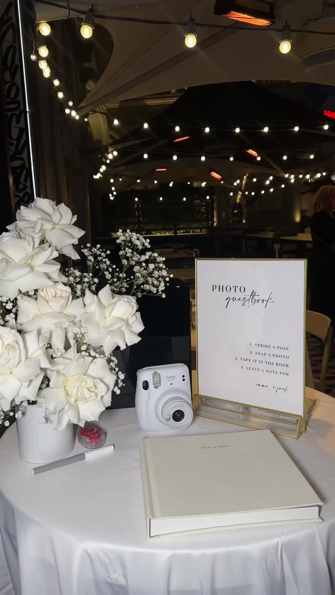 This may contain: a white table with flowers and a book on it that says, you can just not go wrong with a polaroid guest book