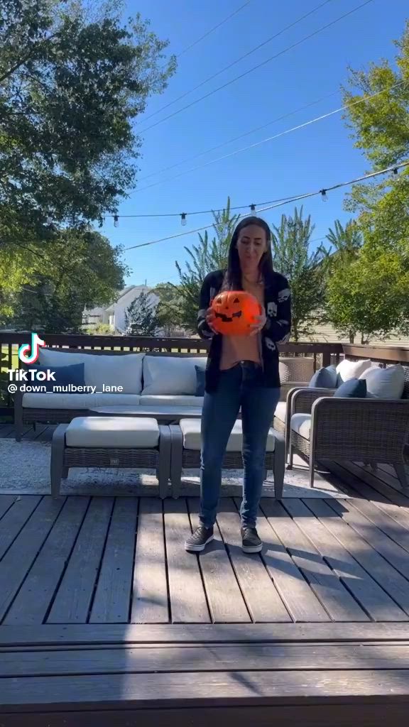 This may contain: a woman holding an orange frisbee on top of a wooden deck