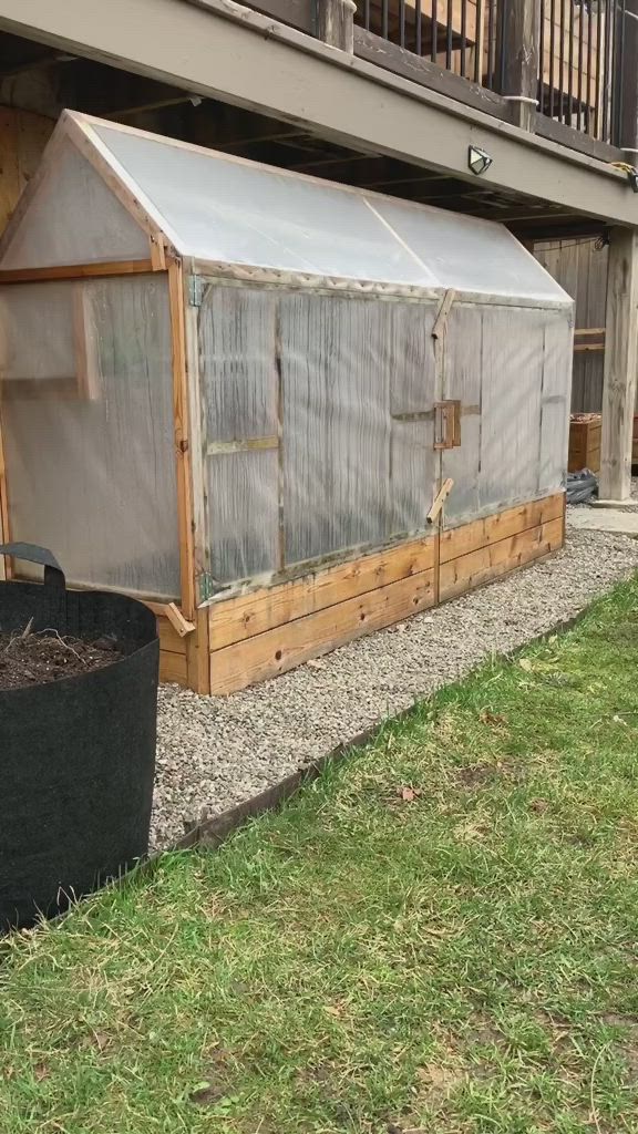 This may contain: a man standing next to a small greenhouse