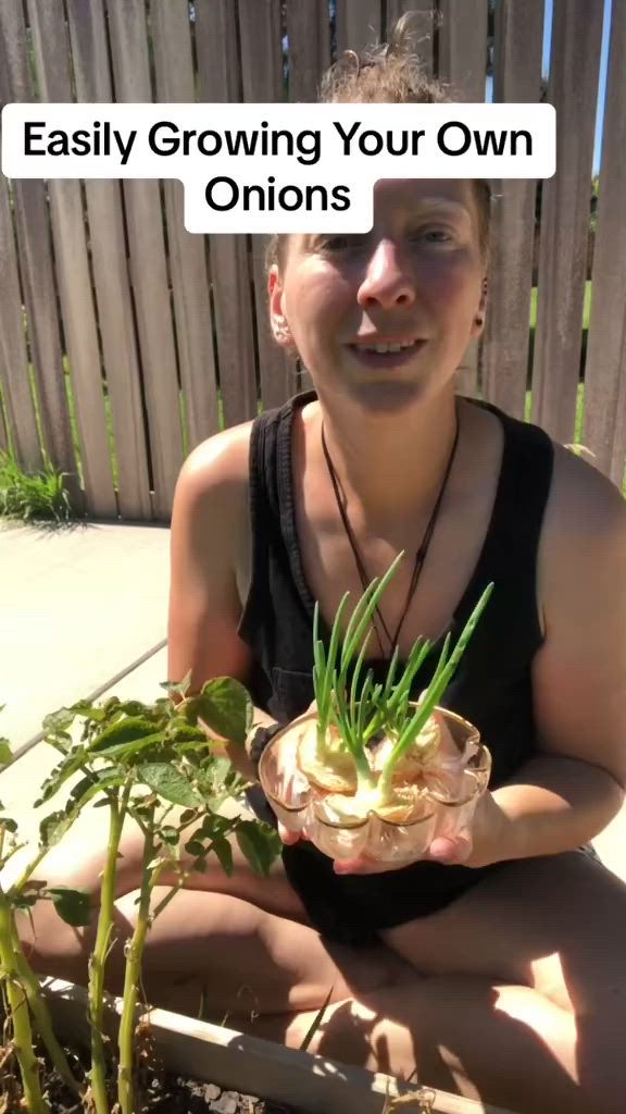 This may contain: a woman sitting on the ground holding a potted plant with an onion in it and text saying, easily growing your own onions so my family